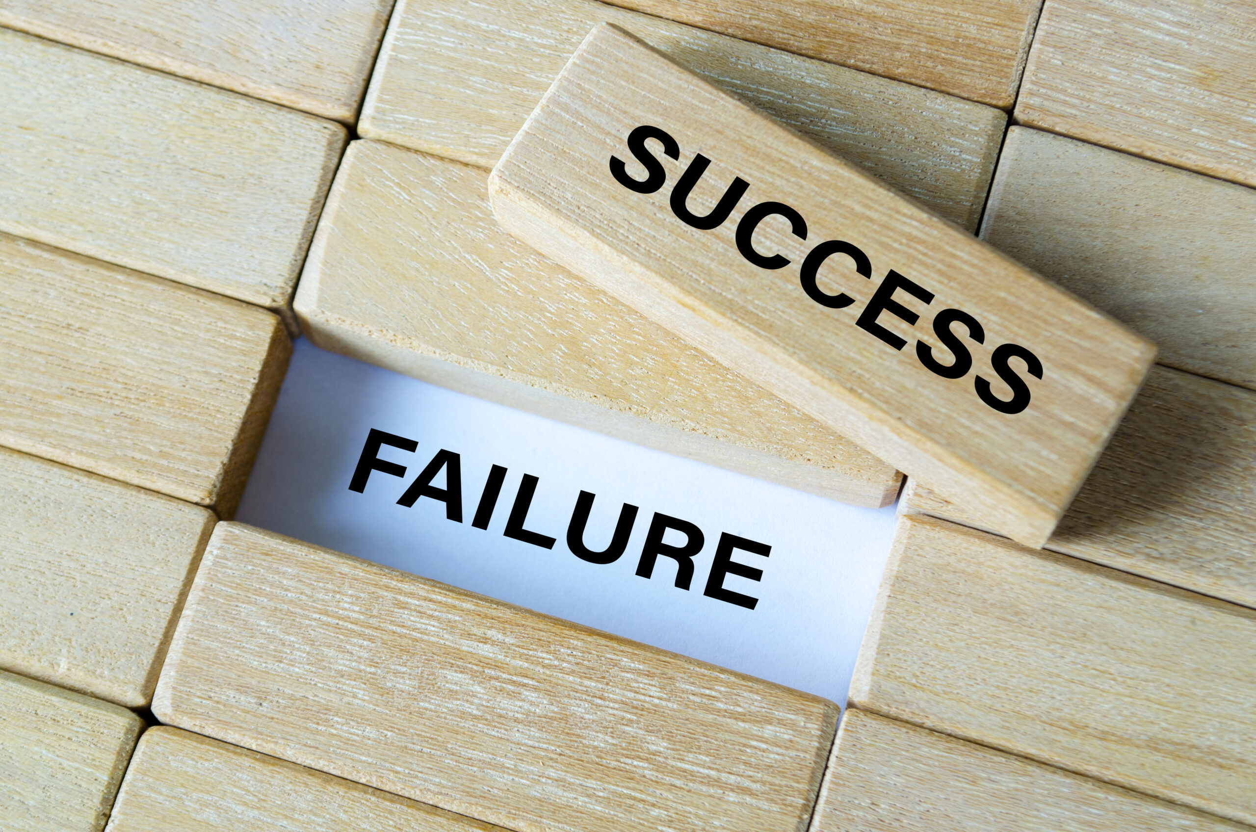 Success and failure text written on wooden blocks showing contrast between achievement and setbacks.